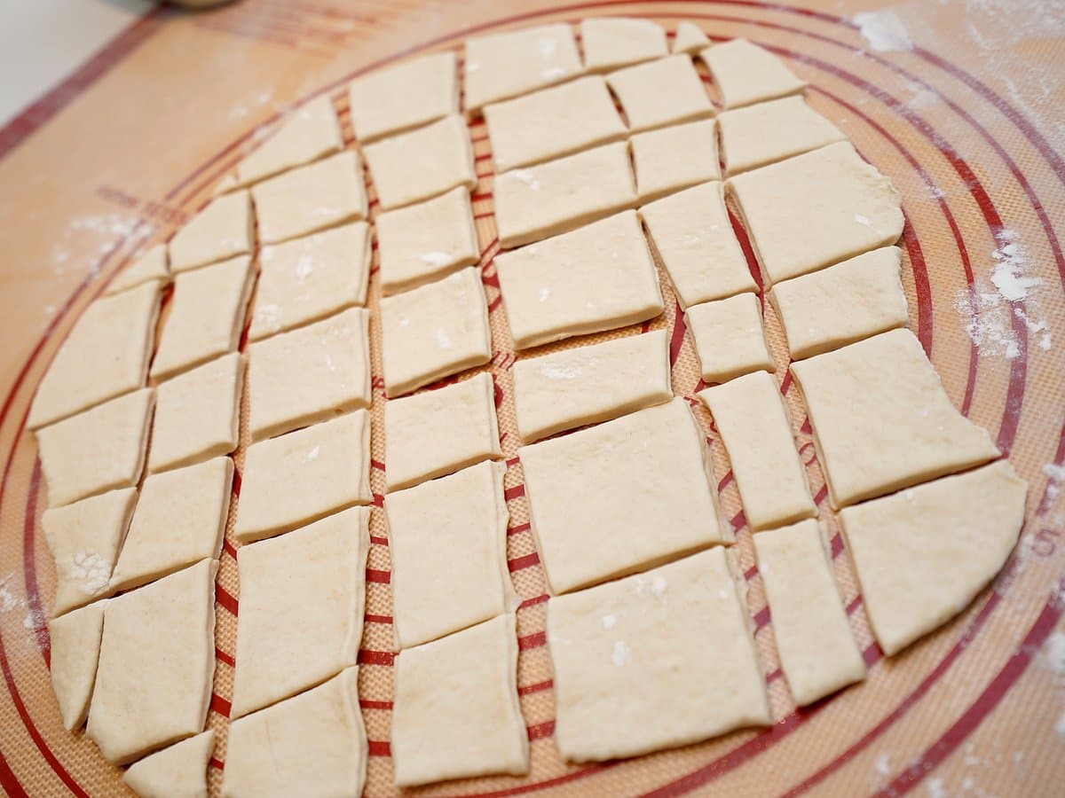 Dough rolled flat and cut into squares with a pizza cutter, ready for frying